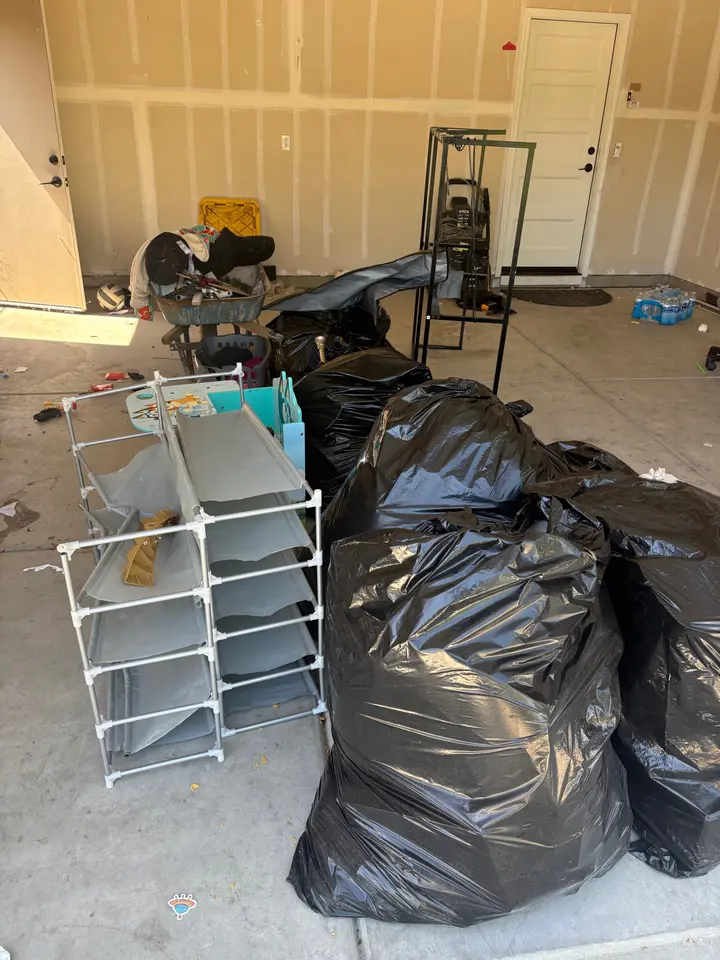 Garage with trash bags and shelving waiting to be hauled away