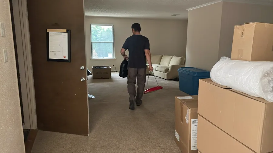 Worker carrying leftover items out of an apartment after a tenant move-out